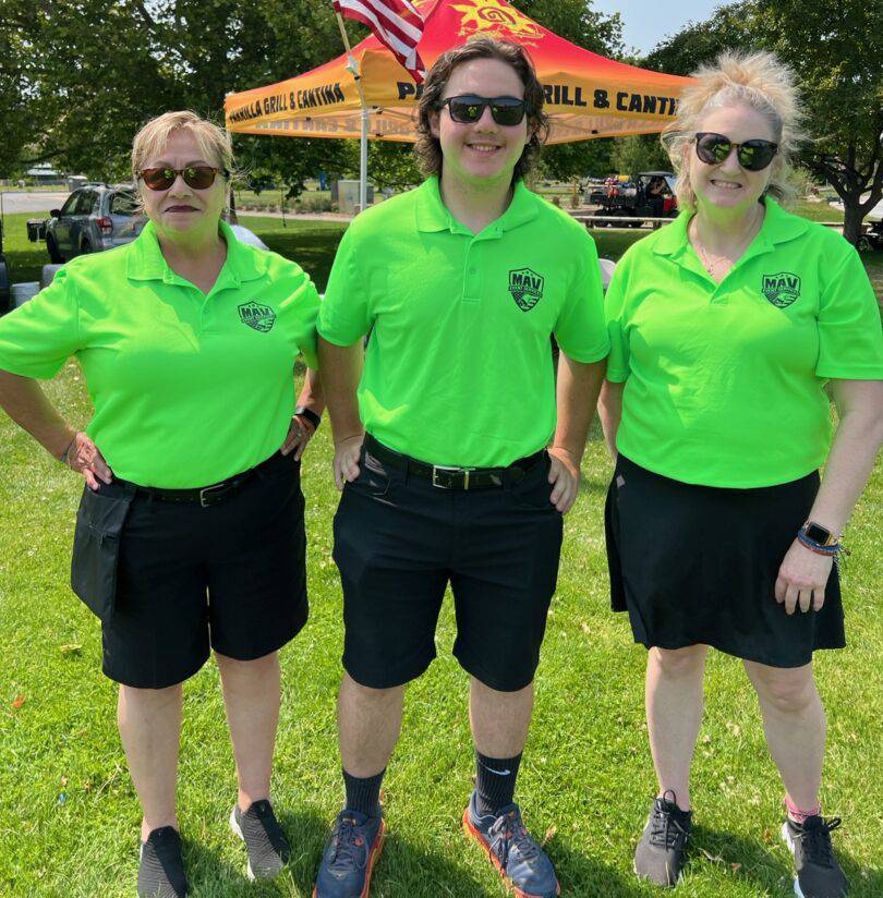 Three people in green shirts and black shorts.